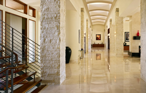 long marble finished hall way with native stone columns that flank it leading to a clerestory