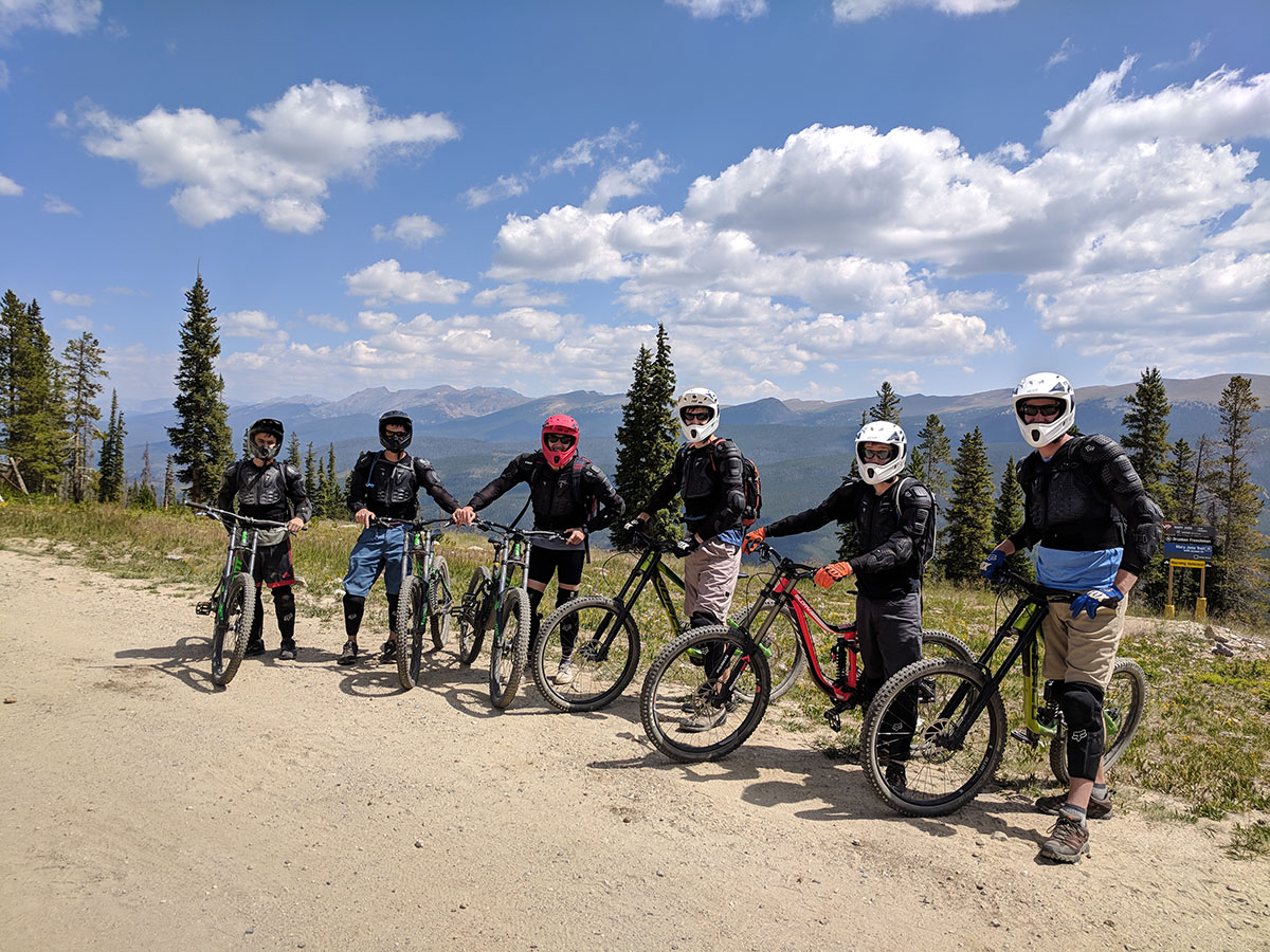 Team posing with mountain bikes against mountain scenery